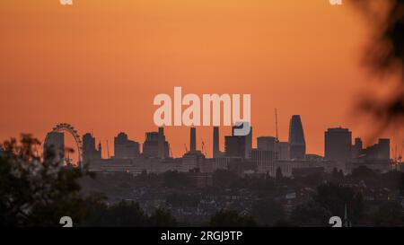 Wimbledon, Londra, Regno Unito. 10 agosto 2023. Temperature a Londra dovute al picco a 25 gradi piacevoli oggi. Un cielo arancione all'alba con ben noti punti di riferimento a Londra. Da sinistra a destra: London Eye, Houses of Parliament, Battersea Power Station. Crediti: Malcolm Park/Alamy Live News Foto Stock