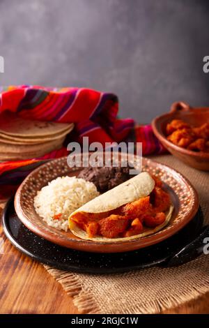 Chicharron en salsa roja. Croste di maiale stufate in salsa rossa accompagnate da riso e fagioli fritti. Piatto tradizionale fatto in casa molto popolare in Messico, questo Foto Stock