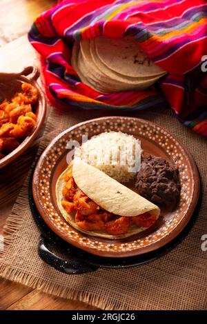 Chicharron en salsa roja. Croste di maiale stufate in salsa rossa accompagnate da riso e fagioli fritti. Piatto tradizionale fatto in casa molto popolare in Messico, questo Foto Stock