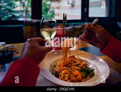 Spaghetti con gamberoni tigre e verdure, un bicchiere di vino bianco e un bicchiere di limonata di fragole Foto Stock