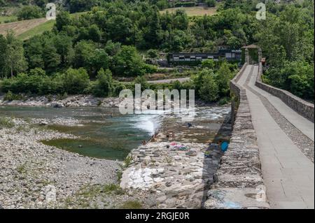 Il fiume Trebbia visto dall'antico ponte a gobbo di Bobbio, in un giorno d'estate con la gente che fa il bagno in acqua Foto Stock