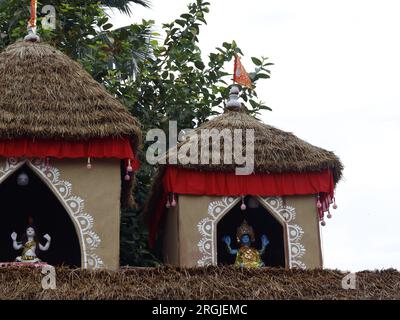 Una capanna indiana chiamata tempio hindu shiv bishnu fatta di fango e legno. Il tetto è fatto di rami. Vegetazione sullo sfondo Foto Stock