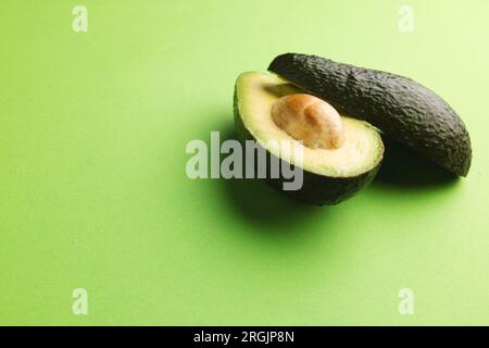 Primo piano di due metà di avocado e spazio di copia su sfondo verde Foto Stock