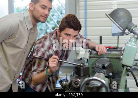 un ritratto dei lavoratori che guardano un'esercitazione sul banco Foto Stock