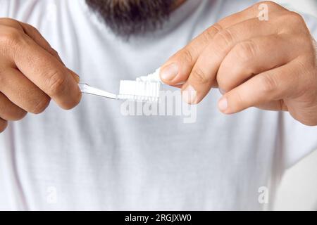 Immagine ritagliata di mani maschili che applicano il dentifricio sullo spazzolino. Prestare attenzione dopo i denti. Cura della bocca dentale Foto Stock