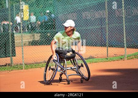 L'uomo pratica tennis su una sedia a rotelle su un campo in terra battuta. Tennis su sedia a rotelle. Foto Stock