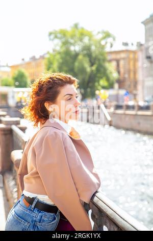 Ritratto alla moda di una giovane donna elegante che cammina lungo l'argine. Giornata estiva di sole a San Pietroburgo. Foto Stock