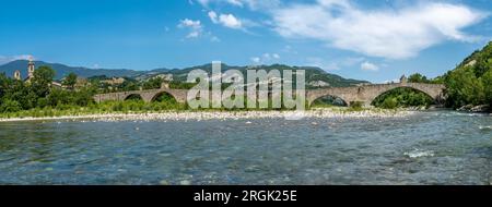 Il fiume Trebbia scorre sotto l'antico ponte di Gobbo a Bobbio, in Italia Foto Stock