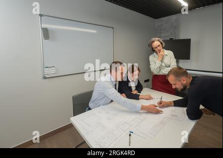 L'estrusione femminile valuta il lavoro dei subordinati. Progettisti ingegneri a una riunione. Foto Stock