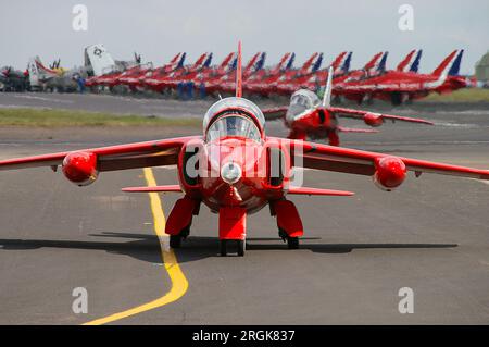 Red Gnat display Team Folland Gnat T1 Jets che si stanno radunando per un airshow, un'esposizione aerea, con gli attuali aerei a reazione della RAF Red Arrows Hawk allineati oltre Foto Stock
