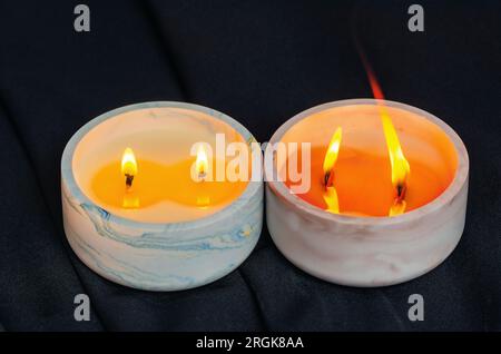 Le candele decorative bruciano nell'appartamento su sfondo nero Foto Stock