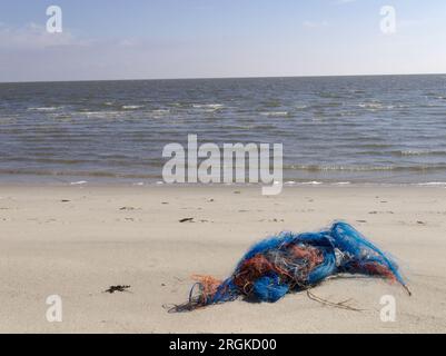 Spazzatura sulla spiaggia. spazzatura, rifiuti sulla spiaggia di sabbia soffice nelle belle giornate estive. Vecchia rete da pesca sulla spiaggia dell'isola Sylt. Foto Stock