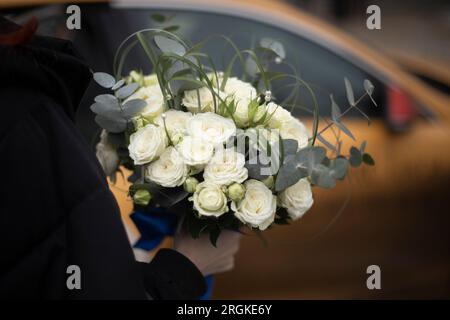 Bouquet di rose per la sposa. Fiori bianchi. Bel bouquet in mano all'uomo. Decorazione femminile. Foto Stock