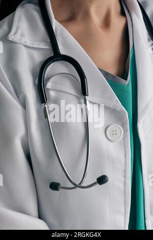 Crop medico femminile irriconoscibile in accappatoio medico bianco con bottoni e stetoscopio in acciaio inox Foto Stock