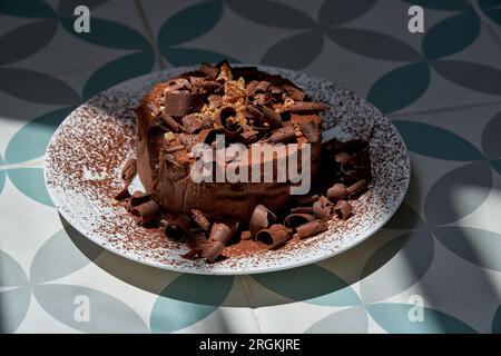 Squisita torta al cioccolato decorata con trucioli e cacao in polvere servita sul piatto Foto Stock