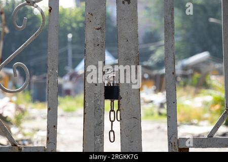 Una serratura su una catena pende su un cancello di ferro, chiuso, accesso negato Foto Stock