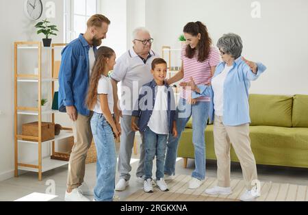 La grande famiglia felice si congratula con il figlio e il nipote che stanno a casa in salotto. Foto Stock