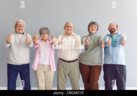 Ritratto di una persona anziana sorridente che guarda la fotocamera con il pollice in alto. Foto Stock