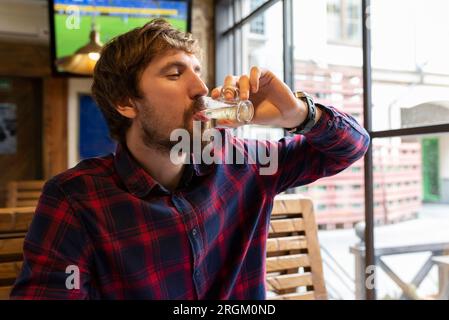 L'uomo solitario in depressione beve una bevanda alcolica forte al bar. Foto Stock