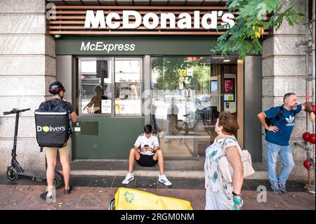 I lavoratori delle Start-up spagnole di consegne on demand, Glovo e Deelivers, attendono presso la multinazionale americana McDonald's, la catena di ristoranti di hamburger fast-food, affinché gli ordini siano pronti per essere ritirati in Spagna. Foto Stock