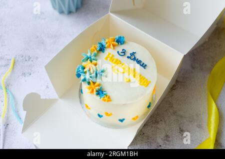 Torta bento alla moda con un'iscrizione blu-gialla in ucraino "buon compleanno" su sfondo chiaro. Torta di compleanno, torta Bento per due Ukrai Foto Stock