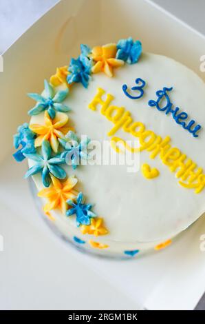 Torta bento alla moda con un'iscrizione blu-gialla in ucraino "buon compleanno" su sfondo chiaro. Torta di compleanno, torta Bento per due Ukrai Foto Stock