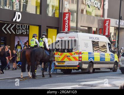 Gli agenti di polizia sorvegliano JD Sports su Oxford Street. Secondo quanto riferito, un post sui social media ha organizzato un evento di taccheggio di massa nella trafficata strada dello shopping nel centro di Londra, con la polizia che arrestava e si scontrava con diversi giovani fuori dai negozi durante il giorno. Foto Stock