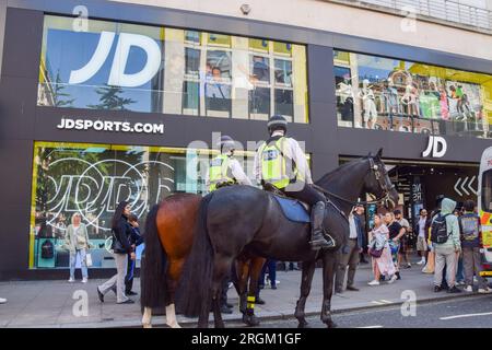 Gli agenti di polizia a cavallo sorvegliano JD Sports a Oxford Street. Secondo quanto riferito, un post sui social media ha organizzato un evento di taccheggio di massa nella trafficata strada dello shopping nel centro di Londra, con la polizia che arrestava e si scontrava con diversi giovani fuori dai negozi durante il giorno. Foto Stock