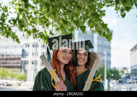 Due giovani donne si sono recentemente diplomate all'università mostrando i loro titoli. Concetto: Istruzione, formazione, apprendimento Foto Stock