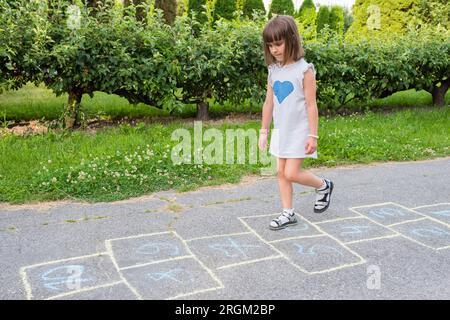 Il bambino gioca sul marciapiede nei giochi per bambini Foto Stock