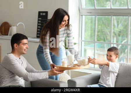 Giovane donna che porta il vassoio con latte e biscotti alla sua famiglia a casa Foto Stock