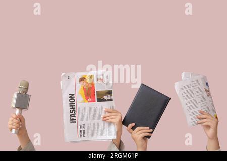 Mani femminili con giornali, notebook e microfono su sfondo a colori Foto Stock