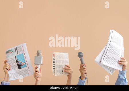 Mani femminili con microfoni e giornali su sfondo a colori Foto Stock