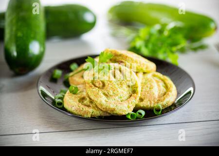 Fritti pancake verdi di zucca in un piatto, su un tavolo di legno. Foto Stock