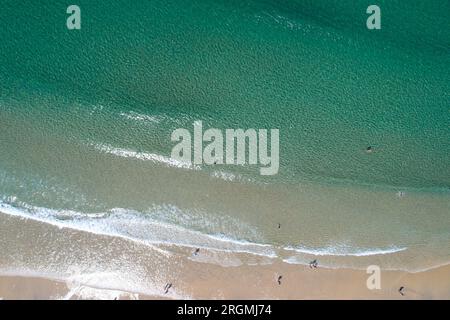 vista aerea zenithal di una spiaggia con le persone che si godono l'estate, facendo il bagno nel mare. Foto Stock