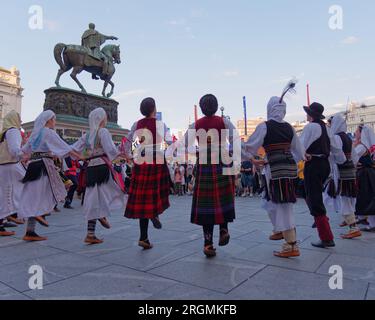 Piazza della Repubblica con persone in costumi tradizionali che ballano di fronte al Monumento del Principe Mihailo, nella città di Belgrado, Serbia, 10 agosto 2023. Foto Stock