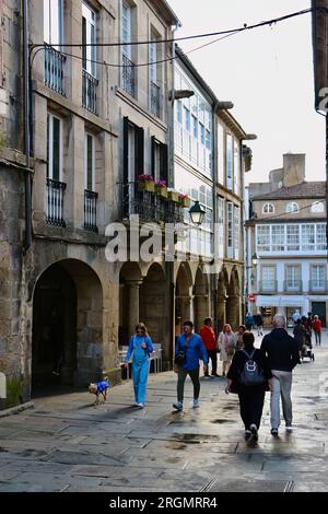 I turisti in una giornata umida di giugno in una stretta strada pedonale del centro storico Santiago de Compostela Galizia Spagna Foto Stock