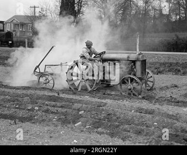 Agricoltore su un trattore Ford che ara un campo circa 1925 Foto Stock