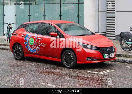 Londra, Regno Unito - 30 luglio 2023; Red Zipcar con logo del marchio parcheggiata su Wet City of London Street Foto Stock