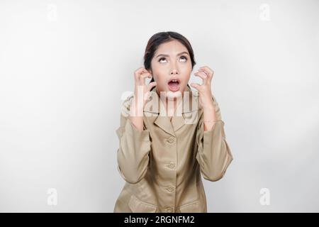 Una lavoratrice civile pazza che indossa un'uniforme marrone è così stressata. Concetto di lavoro eccessivo da parte dei dipendenti governativi indonesiani. Foto Stock