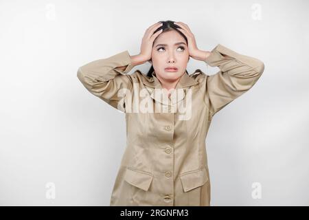 Una lavoratrice civile pazza che indossa un'uniforme marrone è così stressata. Concetto di lavoro eccessivo da parte dei dipendenti governativi indonesiani. Foto Stock