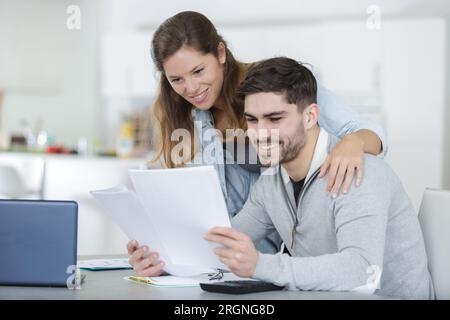 coppia sorridente che utilizza un notebook per occuparsi delle bollette Foto Stock
