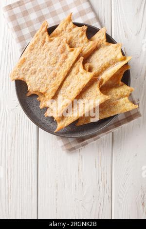 Oreillettes deliziosamente leggeri e croccanti frittelle di pasticceria primo piano sul piatto sul tavolo di legno. Vista dall'alto verticale Foto Stock