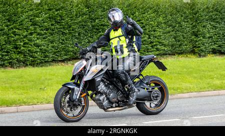 Whittlebury, Northants., UK - 6 agosto 2023. Uomo che indossa pelli da moto nere in sella a una moto KTM attraverso un villaggio inglese. Foto Stock