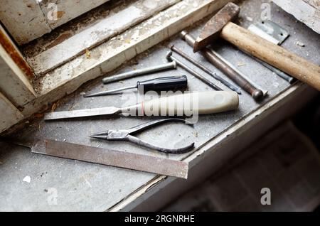 Riparazione del vecchio finestrino danneggiato o smontaggio prima di installare il nuovo primo piano. Riparazione di un telaio di una finestra, utilizzando strumenti per la ristrutturazione di vecchie finestre Foto Stock