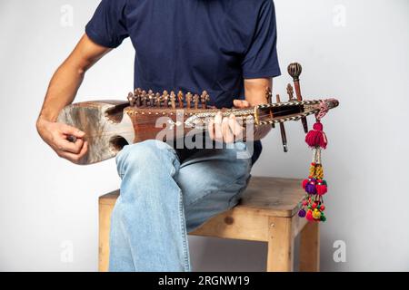 Uomo che suona Rubab uno strumento a corde del popolo orientale del Pakistan settentrionale isolato su sfondo bianco. Foto Stock