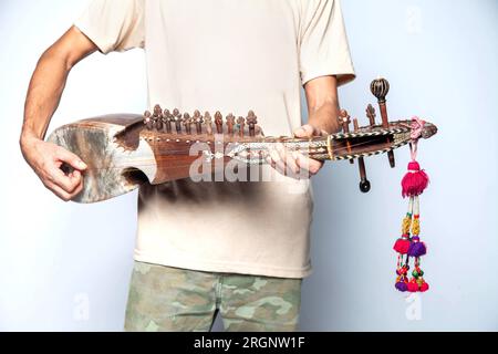 Uomo che suona Rubab uno strumento a corde del popolo orientale del Pakistan settentrionale isolato su sfondo bianco. Foto Stock