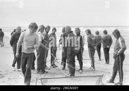 Squadra di football AJAX sulla spiaggia di Wassenaar, giocatori che guardano i pescatori di gamberi, California. Settembre 1972 Foto Stock