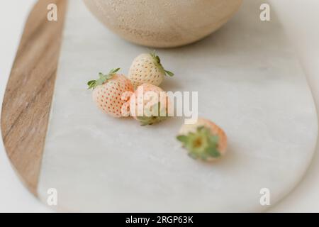 fragole rosa chiaro su tagliere di marmo Foto Stock