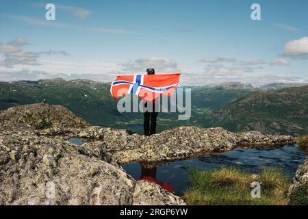 Persona che detiene la bandiera norvegese sulle montagne in Norvegia Foto Stock